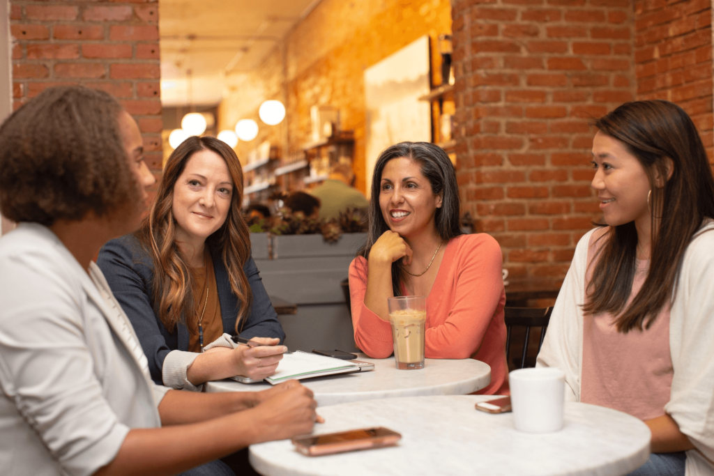 Women engaged in a collaborative discussion around a table, illustrating the concept of organizational coaching and teamwork.